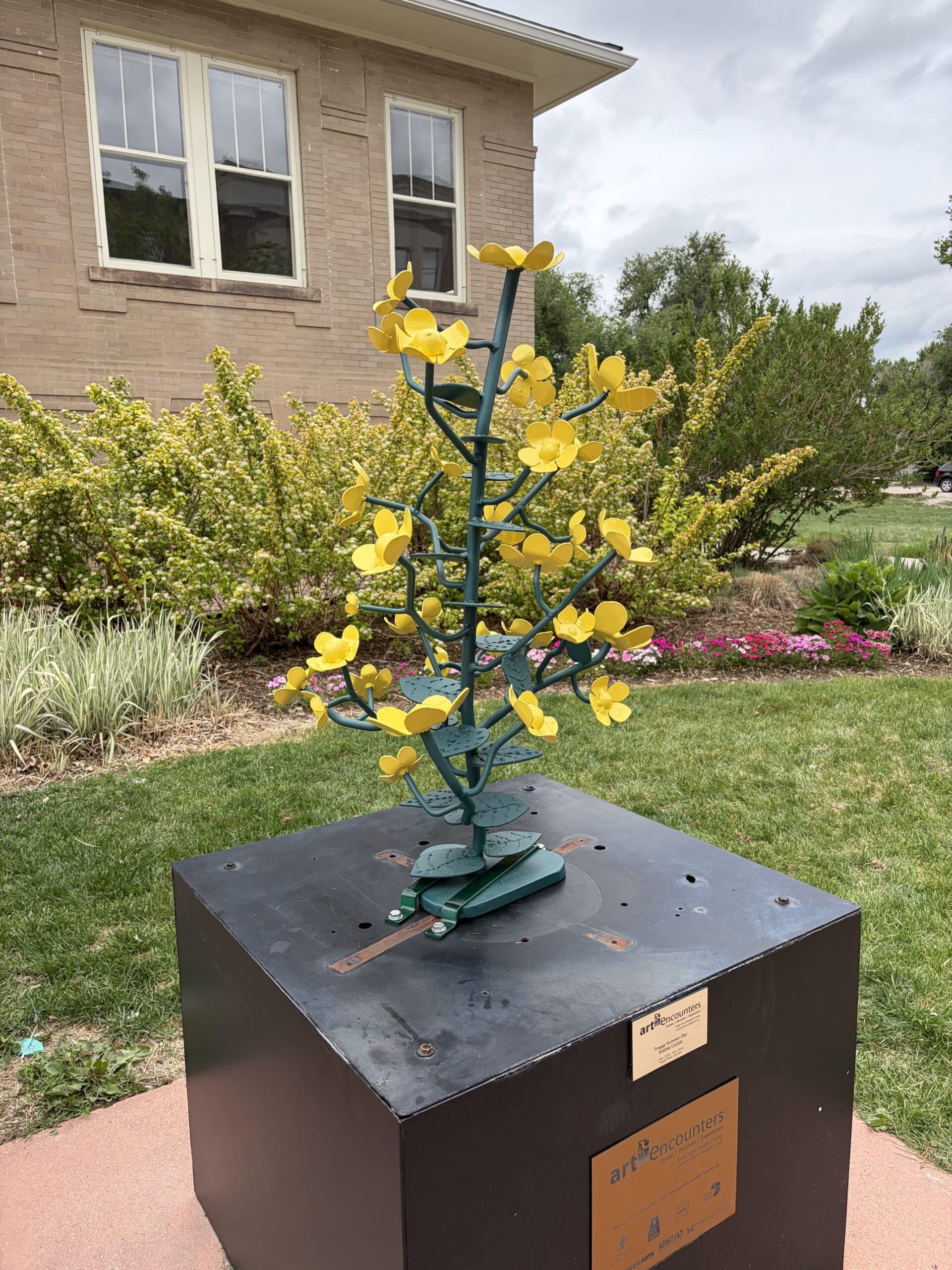 A small powder coated steel sculpture of a striking yellow flower.