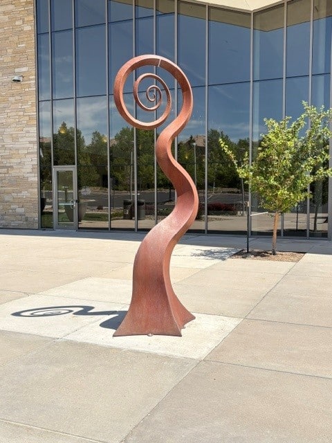 New Sprig is a large abstract steel sculpture that is reminiscent of a new vine springing up from the ground.