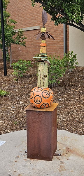 Promise of Summer by artist Charlotte Zink features a cascade of clay orbs, columns, leaves, and hand-carved clay patterns that are stained and glazed with a variety of textures and vibrant colors.