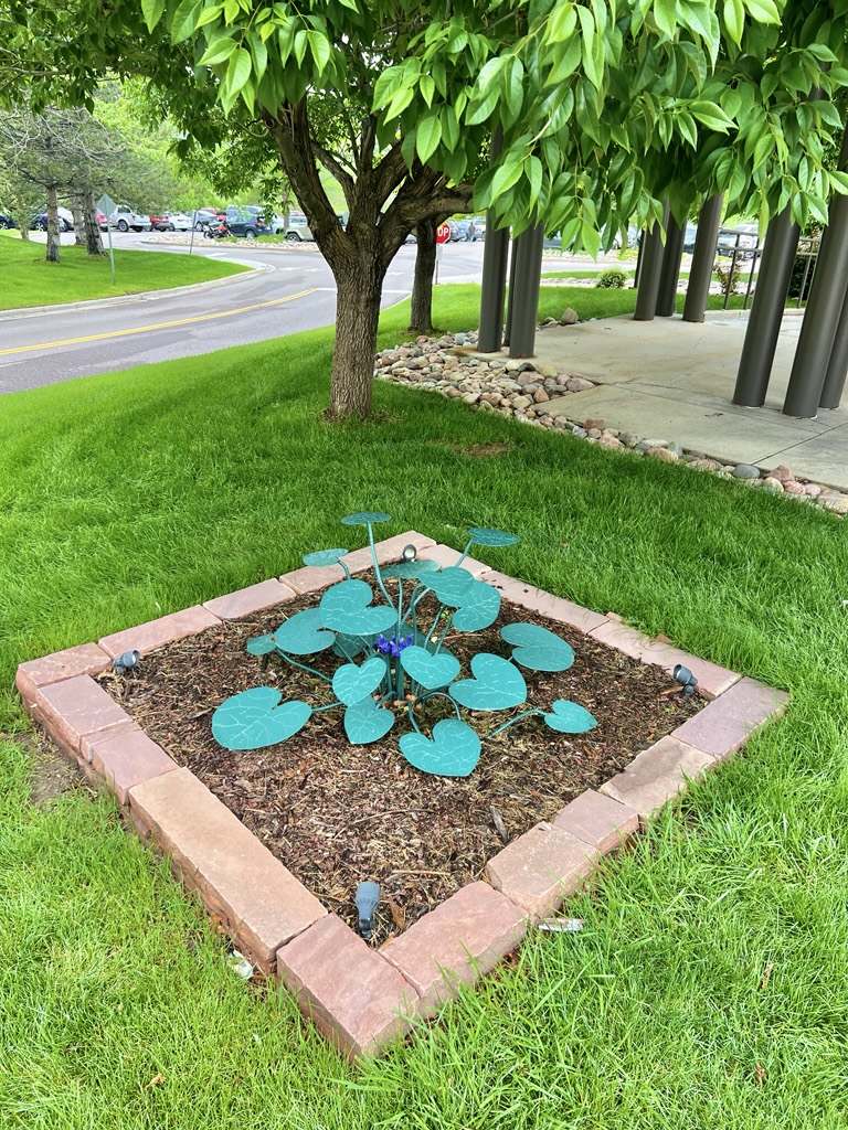 Purple Rebarus is a colorful sculpture with green leaves and purple flowers made of steel.