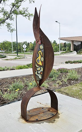 Source by artist Gregory Fields contains a curving of steel forms that cradle two ceramic relief panels.